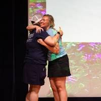Teacher receives hug from Groundswell staff in front of projector background